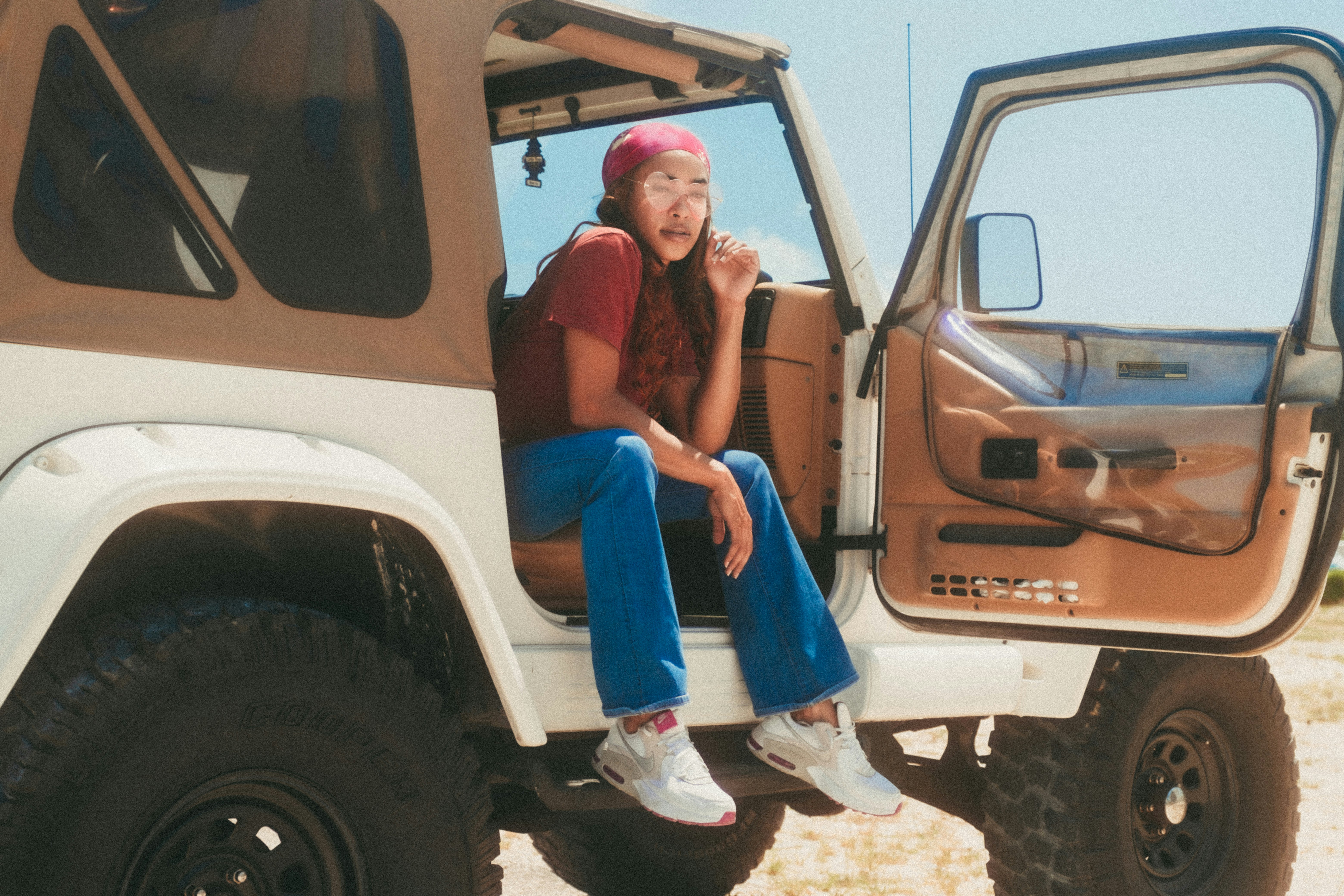 2 women sitting on white car